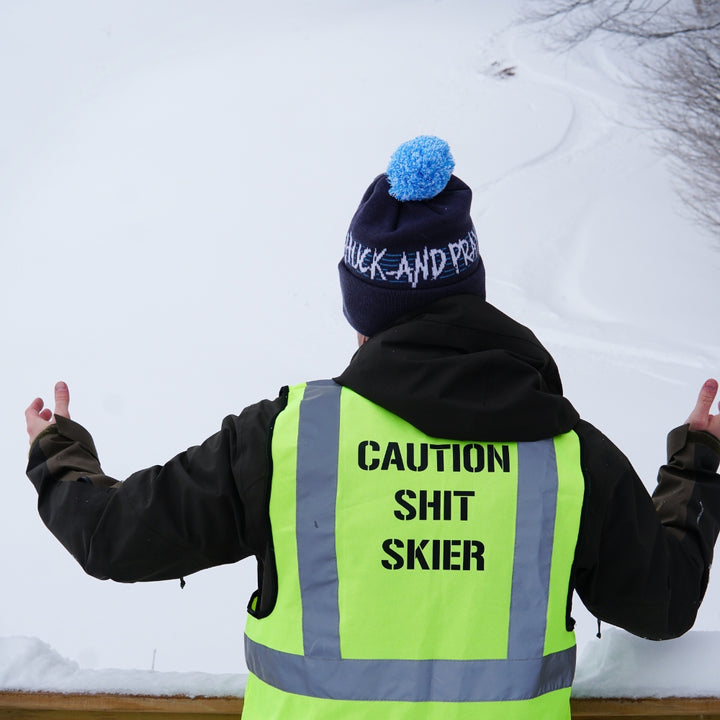 Jerry of the Day Caution Shit Skier Vest, man wearing vest in snow. Funny ski and snowboard gifts, shirts and apparel. 