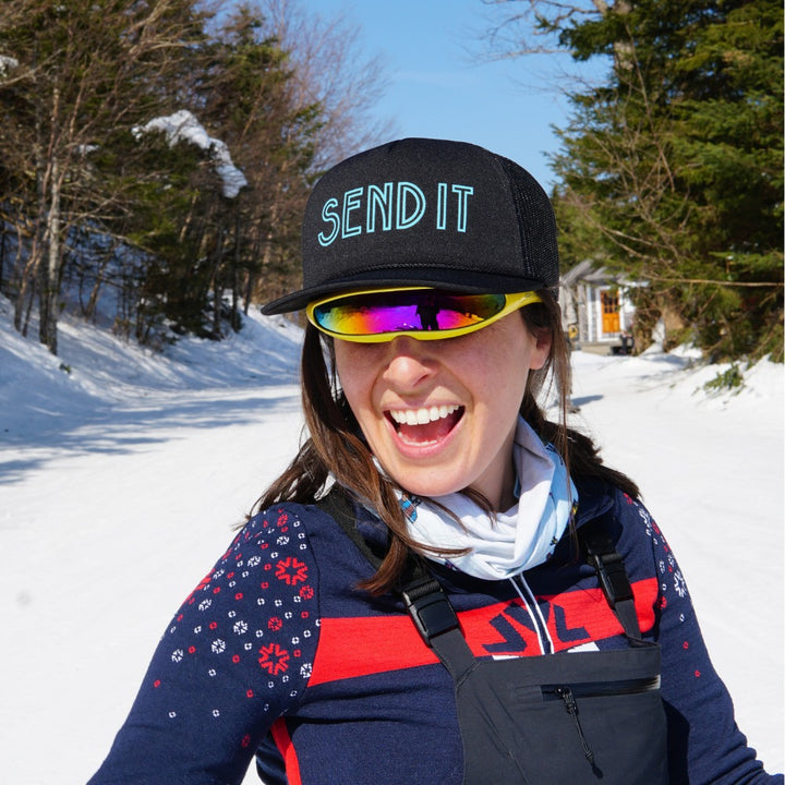 Jerry of the Day Send It Trucker Hat in black, woman wearing while skiing. Funny ski and snowboard gifts, shirts and apparel.