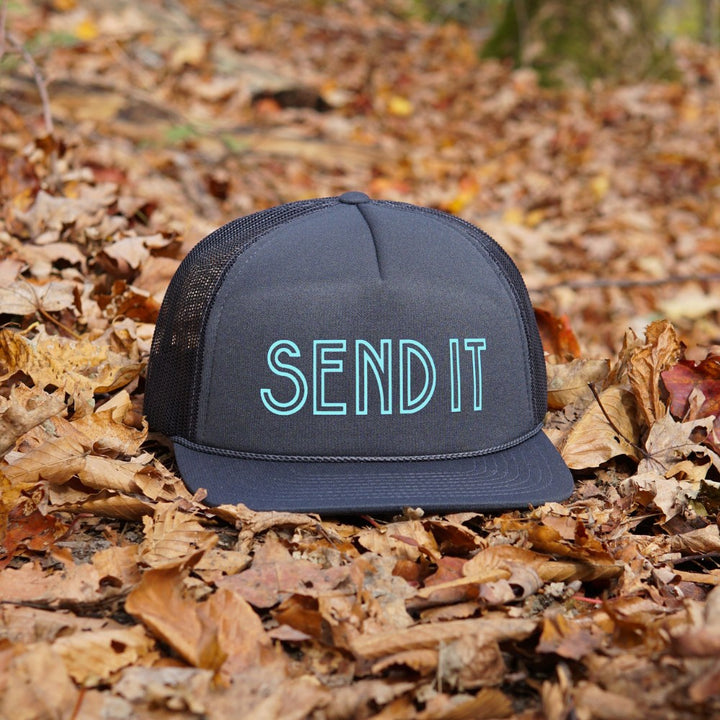 Jerry of the Day Send It Trucker Hat in navy, outside sitting in leaves. Funny ski and snowboard gifts, shirts and apparel.