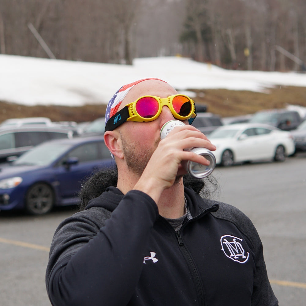 Jerry of the Day Send-O-Vision 2.0 Speed Goggles in yellow, man drinking in parking lot of ski resort. Funny ski and snowboard gifts, shirts, and apparel.