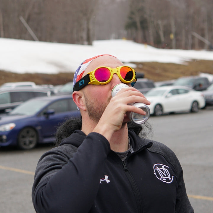 Jerry of the Day Send-O-Vision 2.0 Speed Goggles in yellow, man drinking in parking lot of ski resort. Funny ski and snowboard gifts, shirts, and apparel.