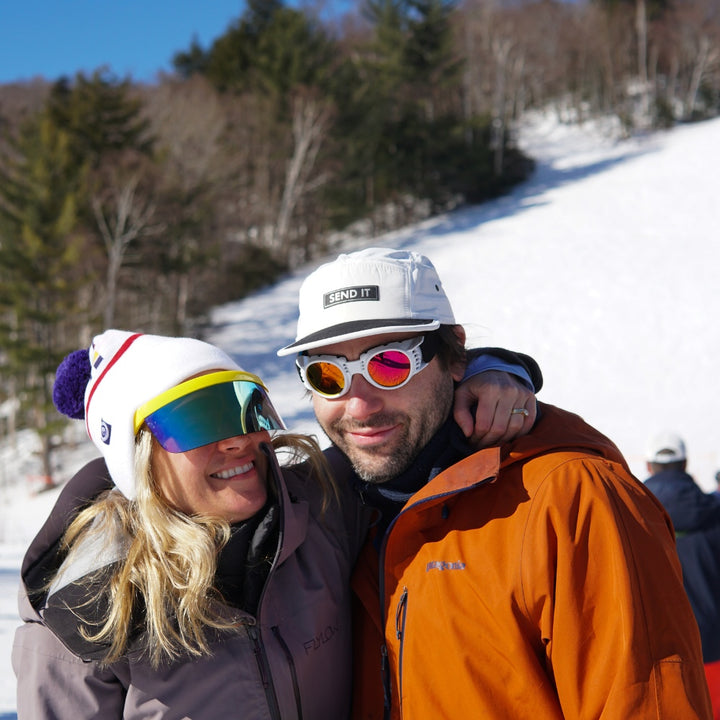 Jerry of the Dayglow Send-O-Vision 3.0 in yellow, woman wearing hugging friend. Funny ski and snowboard gifts, shirts, and apparel.