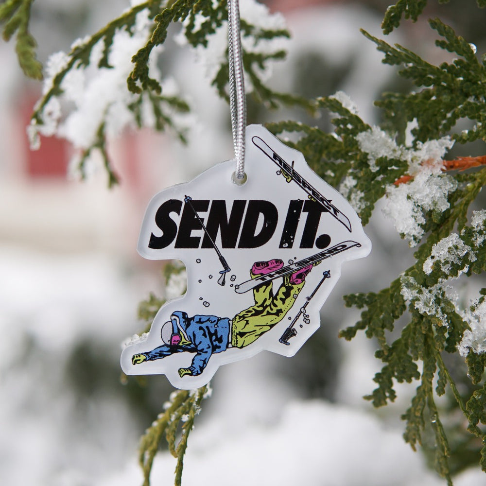 Jerry of the Day Send It Ornament, hanging in snowy tree. Funny ski and snowboard gifts, shirts, and apparel.