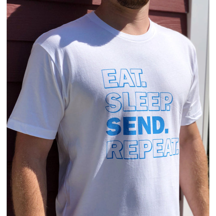 Jerry of the Day Eat Sleep Send Repeat Tee in blue and white, man wearing outside. Funny ski and snowboard gifts, shirts, and apparel.